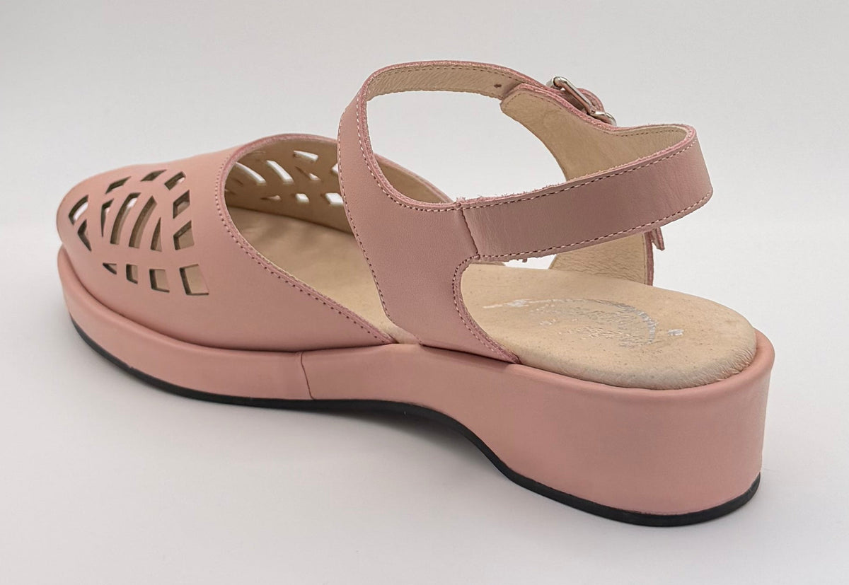 A single light pink wedge sandal with a cutout toe and ankle strap, displayed inside a white lightbox on a black background.