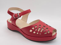 A red platform sandal with a cutout toe and ankle strap, displayed inside a white light box on a black stand.