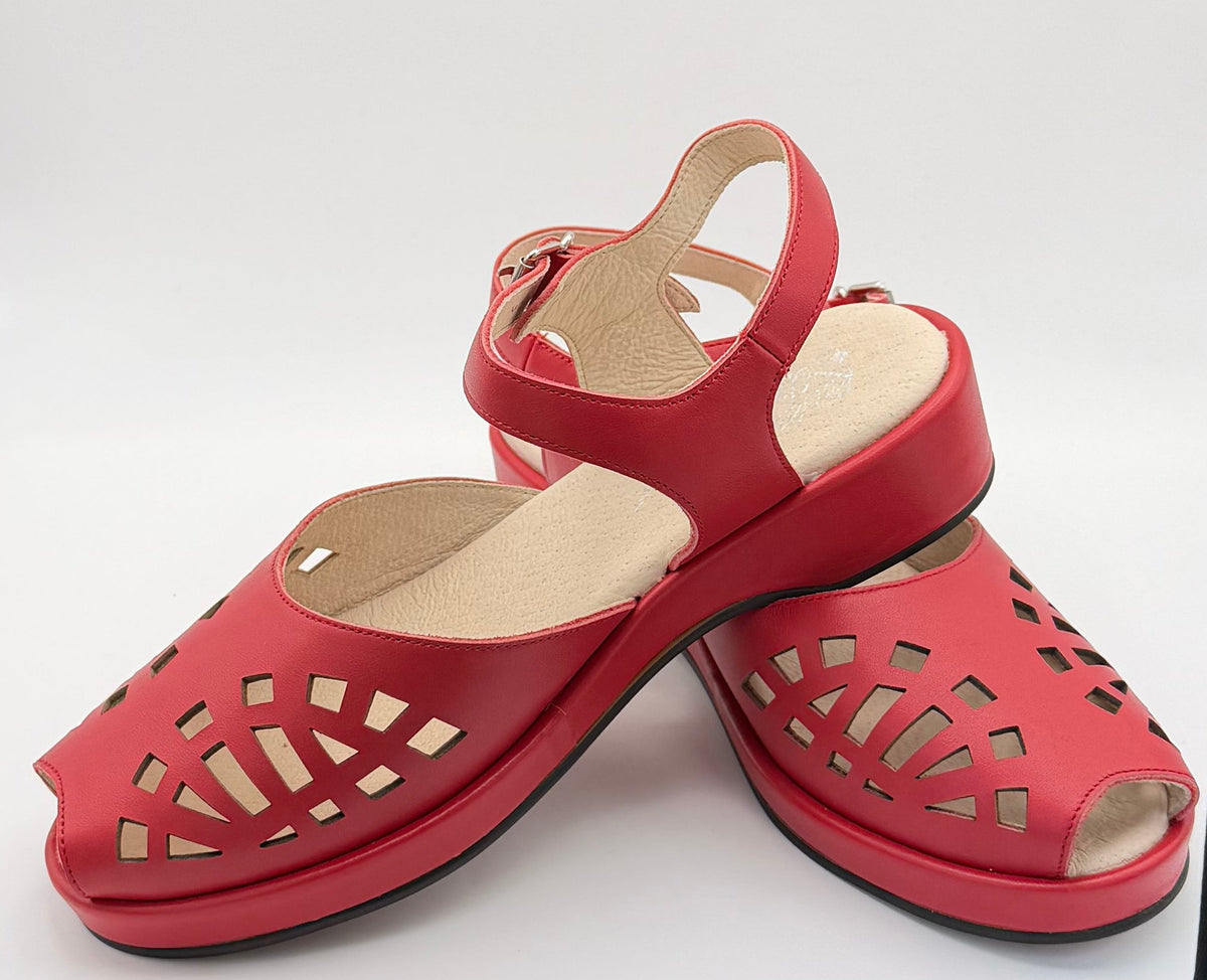 A pair of red cutout vintage sandals with ankle straps, displayed on a white background.