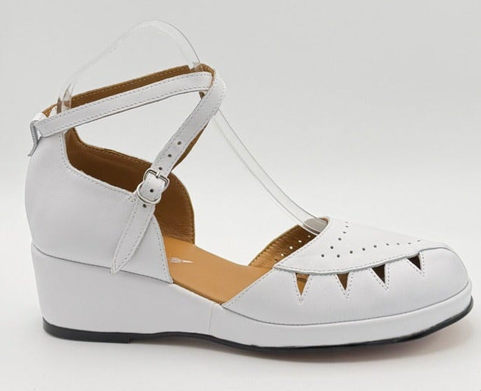 A white vintage wedge sandal with cutout details and an ankle strap.