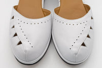 A pair of white leather vintage wedge sandals with cutout details on the toe and crisscross ankle straps.