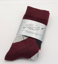 A folded pair of burgundy argyle socks with a silver paper band label.